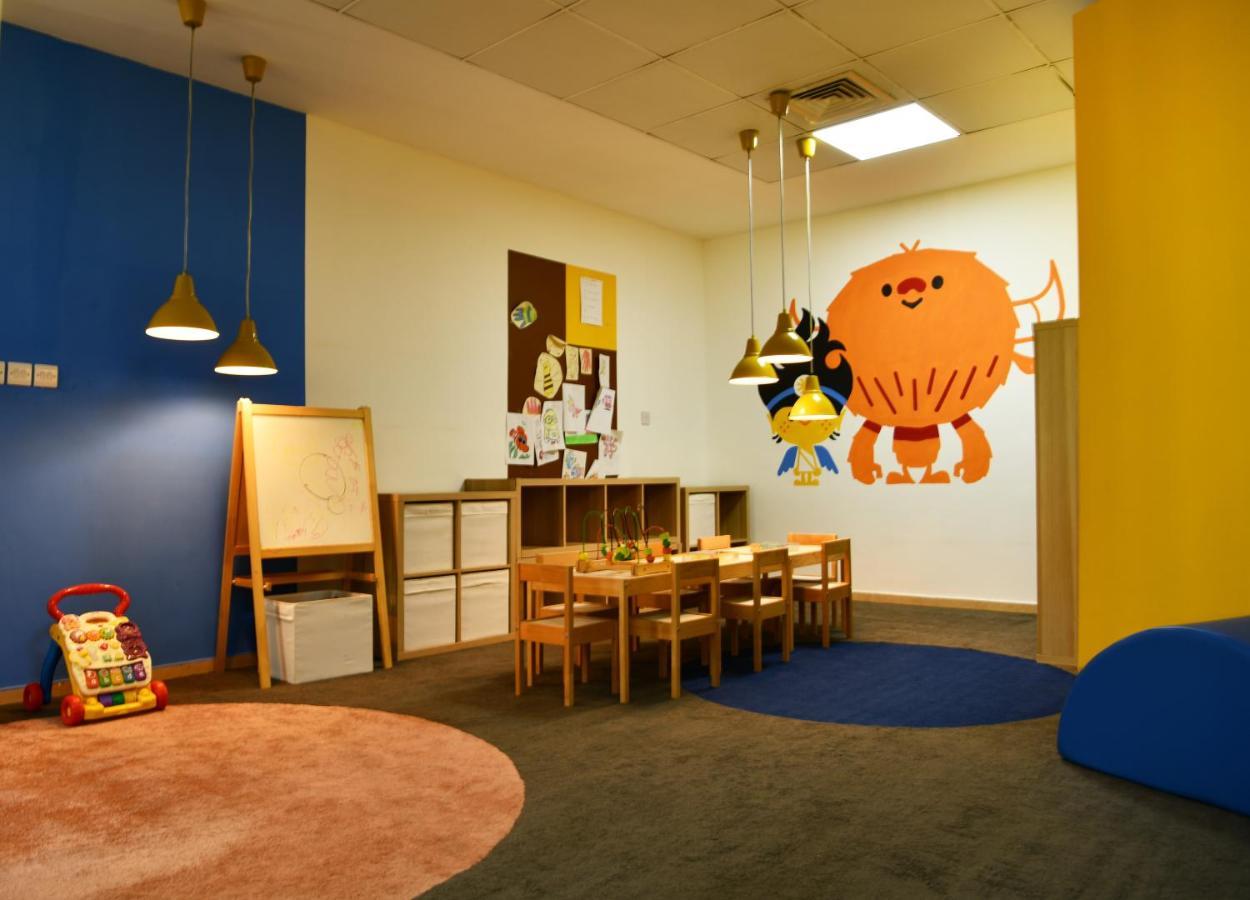 Al Raha Beach Resort & Spa Abu Dabi Exterior foto The photo shows a colorful children's classroom or play area. The walls are painted in various shades, including blue and yellow. There is a large, playful character mural on one wall that appears to be a friendly monster. 

In the room, there is a s