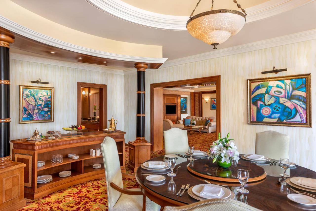 Al Raha Beach Resort & Spa Abu Dabi Exterior foto The photo shows an elegantly designed dining area and a glimpse into a luxurious living space. 

In the foreground, a round dining table is set with fine china, glassware, and a centerpiece featuring fresh flowers. The chairs surrounding the table ha