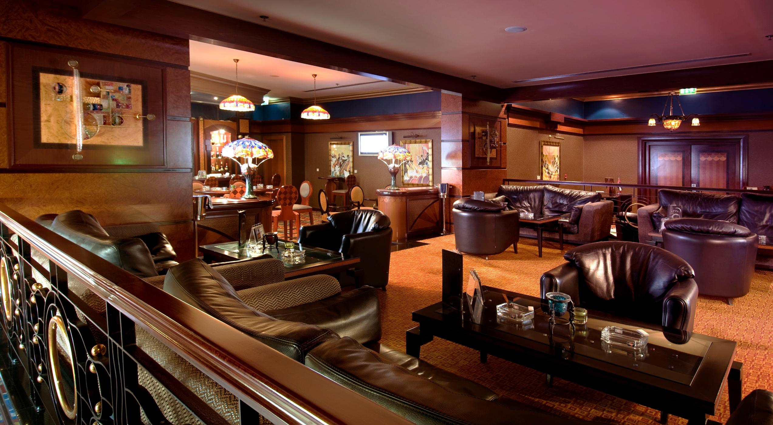 Al Raha Beach Resort & Spa Abu Dabi Interior foto The photo depicts a stylish lounge area featuring comfortable seating and an inviting atmosphere. There are several plush leather armchairs and sofas arranged around low tables. The space is well-lit, with stained glass lamps providing warm light. Th