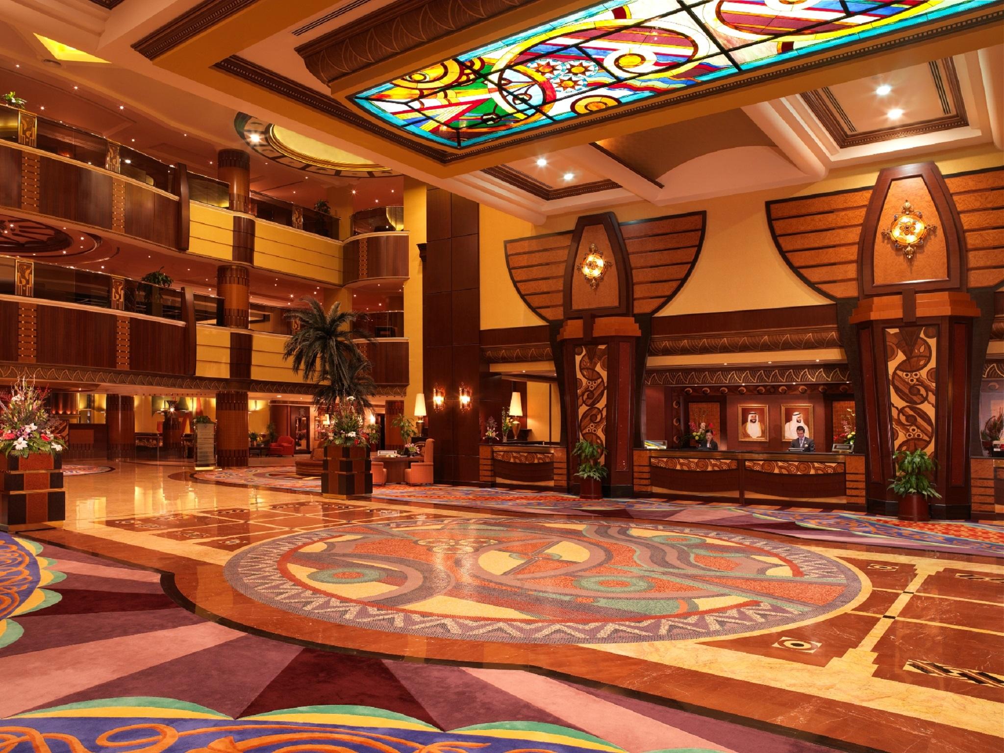 Al Raha Beach Resort & Spa Abu Dabi Interior foto The photo depicts an elegantly designed hotel lobby. It features a grand ceiling with intricate stained glass and decorative patterns. The floor is adorned with colorful, ornate designs, including circular patterns. The lobby is spacious, with wooden