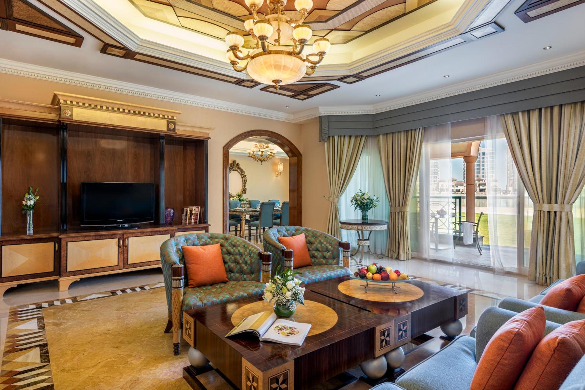 Al Raha Beach Resort & Spa Abu Dabi Exterior foto The photo depicts a luxurious living room with elegant decor. It features two green upholstered sofas accented with orange pillows, arranged around a stylish coffee table. The coffee table showcases decorative items, including a magazine and a bowl o